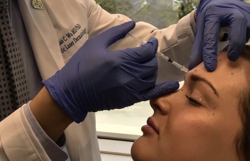 Dermatologist giving a Botox Injection to a female patient to treat frown lines, San Diego, CA