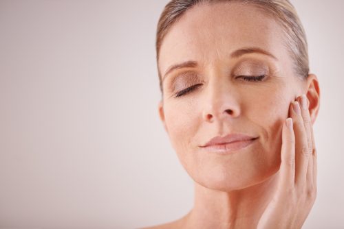 stock image of a woman feeling her skin 