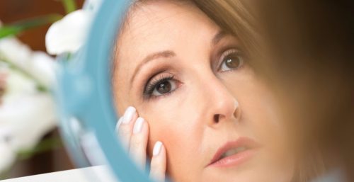 A woman checking the mirror for skin tags at cosmetic laser dermatology in san diego, ca