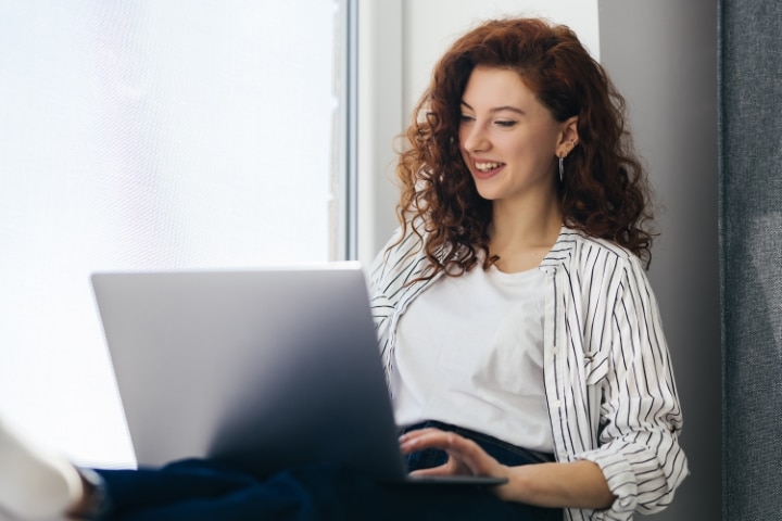 A young woman browsing the internet on a laptop