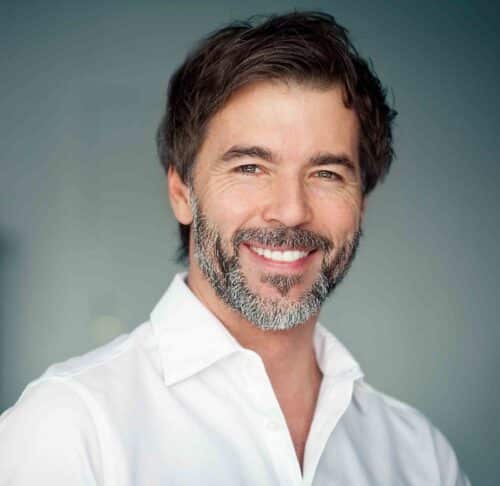 a dark-hair male with a beard smiling headshot