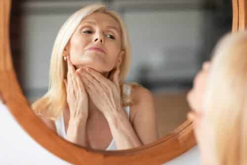 woman looking in mirror and touching neck